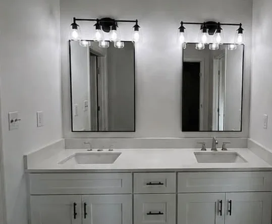 Remodeled bathroom with double vanity, twin mirrors and black bar lighting
