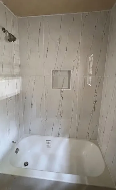 Marble-look tile tub and shower surround with recessed niche