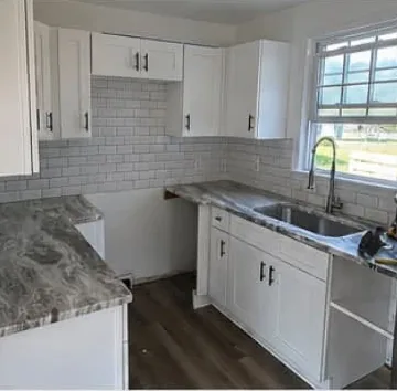 Refreshed kitchen with white shaker cabinets, subway tile backsplash and stone counters