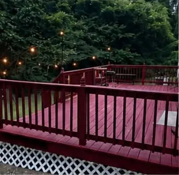 Deck repaired and refinished in deep red stain with string lights overhead